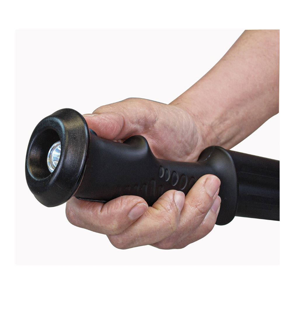 Close-up of a hand gripping the handle of a stun hiking staff with flashlight feature for outdoor safety.